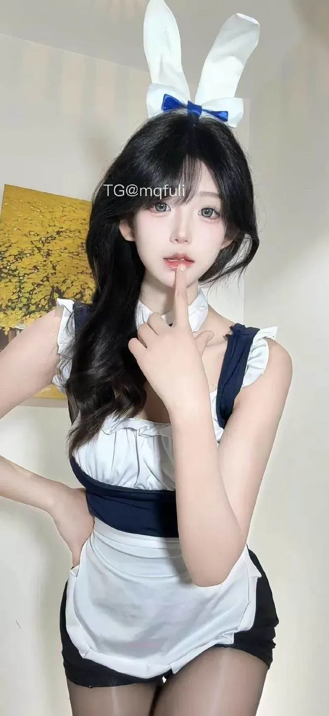 抖音叮咚兔耳角色造型与服装风格阶段整理 白色兔耳与蓝色蝴蝶结搭配蓝白服装,人物正面站立于浅色室内背景前