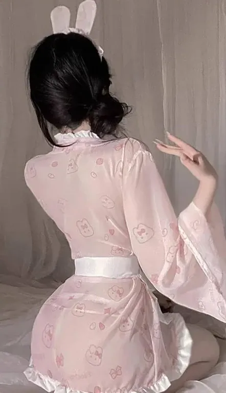 抖音小狼崽粉色造型与角色写真阶段整理 人物佩戴白色兔耳形配饰并穿浅粉宽袖服装背对镜头抬手做手势