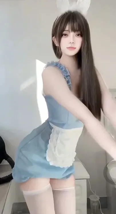 抖音小仙运动穿搭与兔耳女仆风格阶段整理 长发人物佩戴白色兔耳头饰,穿蓝色裙装、白色围裙和浅色长袜站在明亮室内