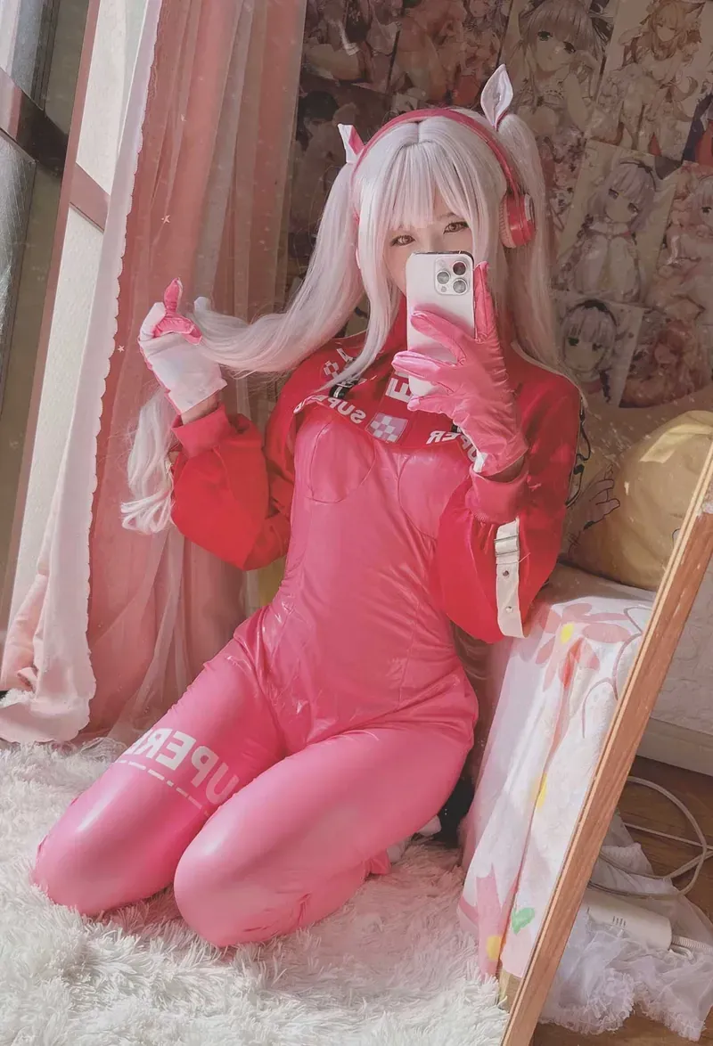 欧翼翼角色扮演服装风格专题 银白色双马尾人物穿粉红色印字服装，搭配耳机与手套，在室内镜前持手机拍摄