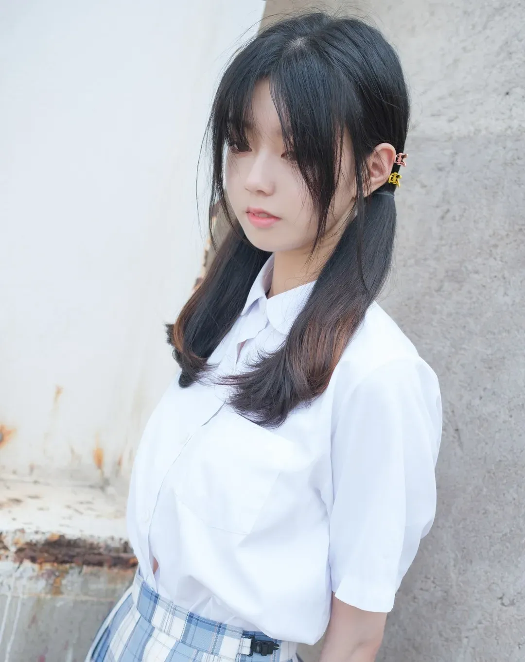稚乖画册角色题材中侧身靠在浅色墙面的双马尾女孩