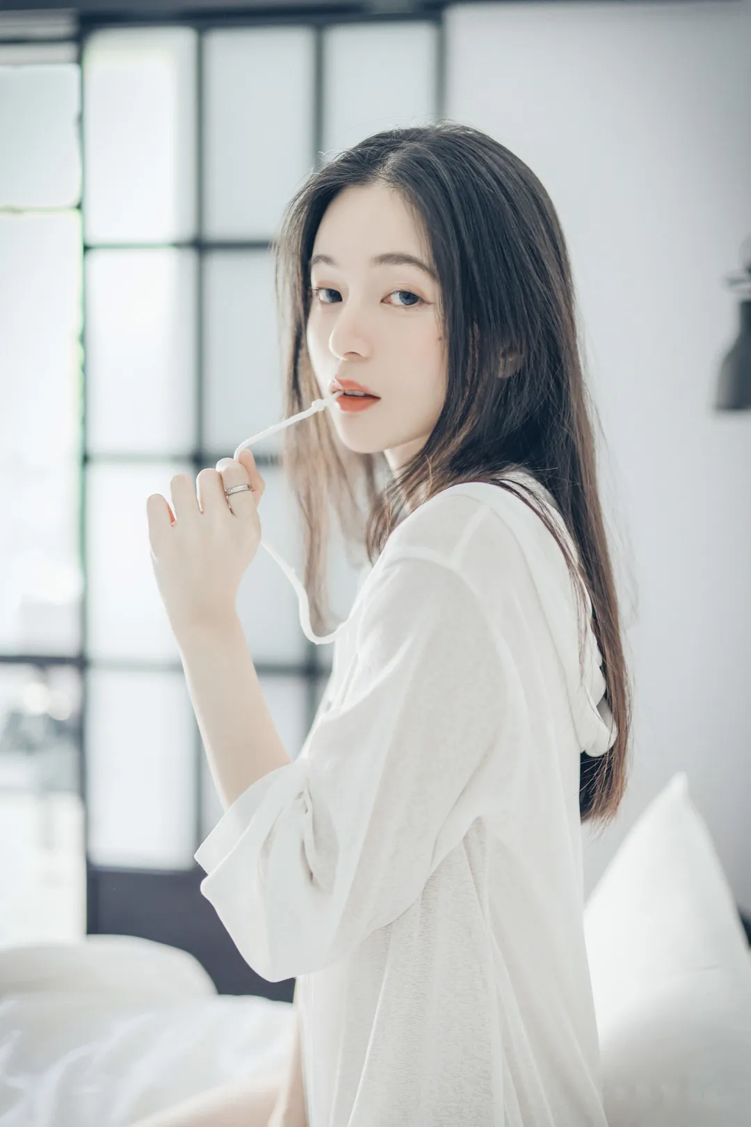 辰辰身穿白色连帽长袖上衣侧身坐在床边