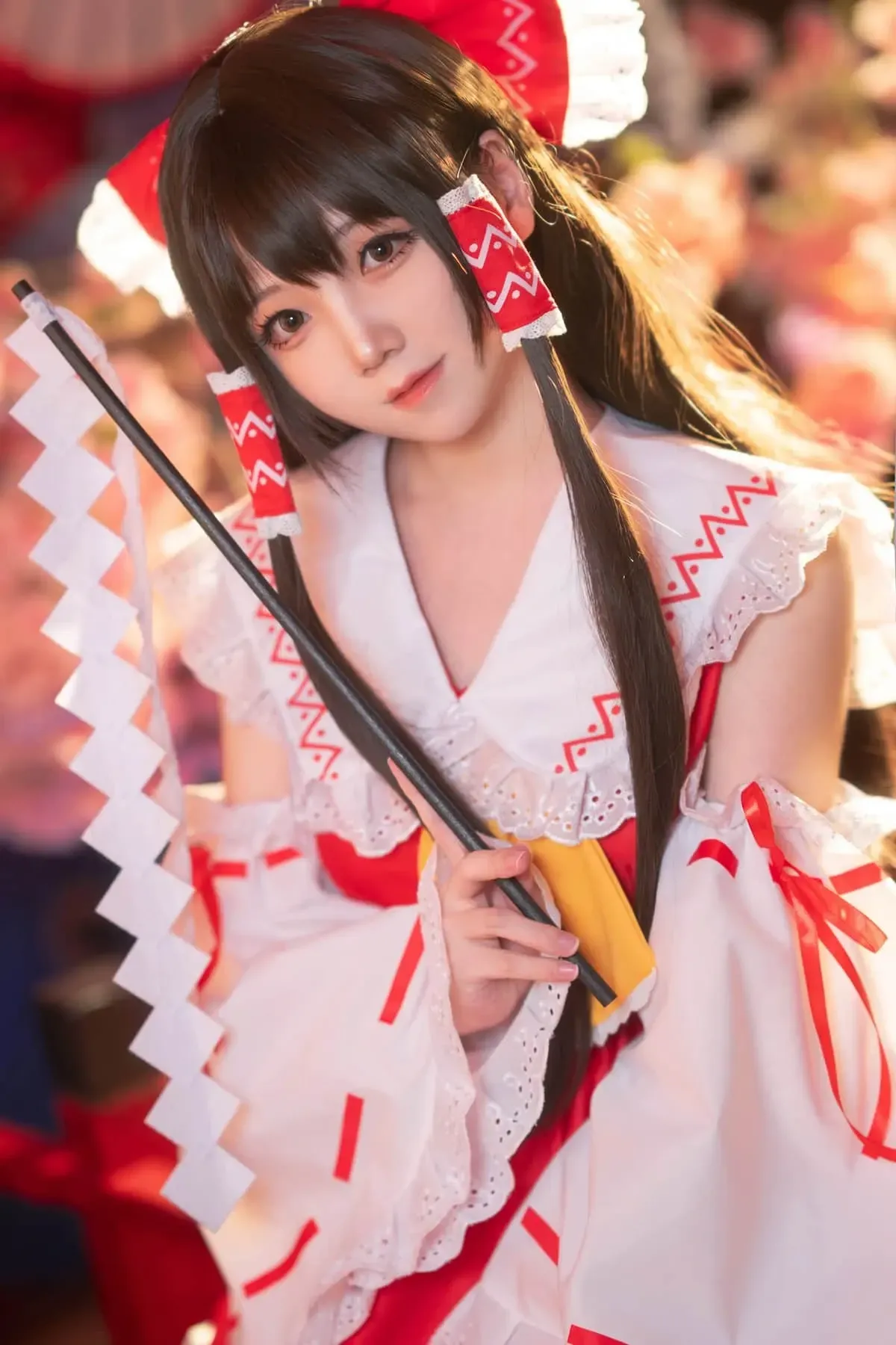 楚楚子w cosplay角色风格作品参考 红白色角色服装搭配黑色长发造型，手持道具的近距离照片
