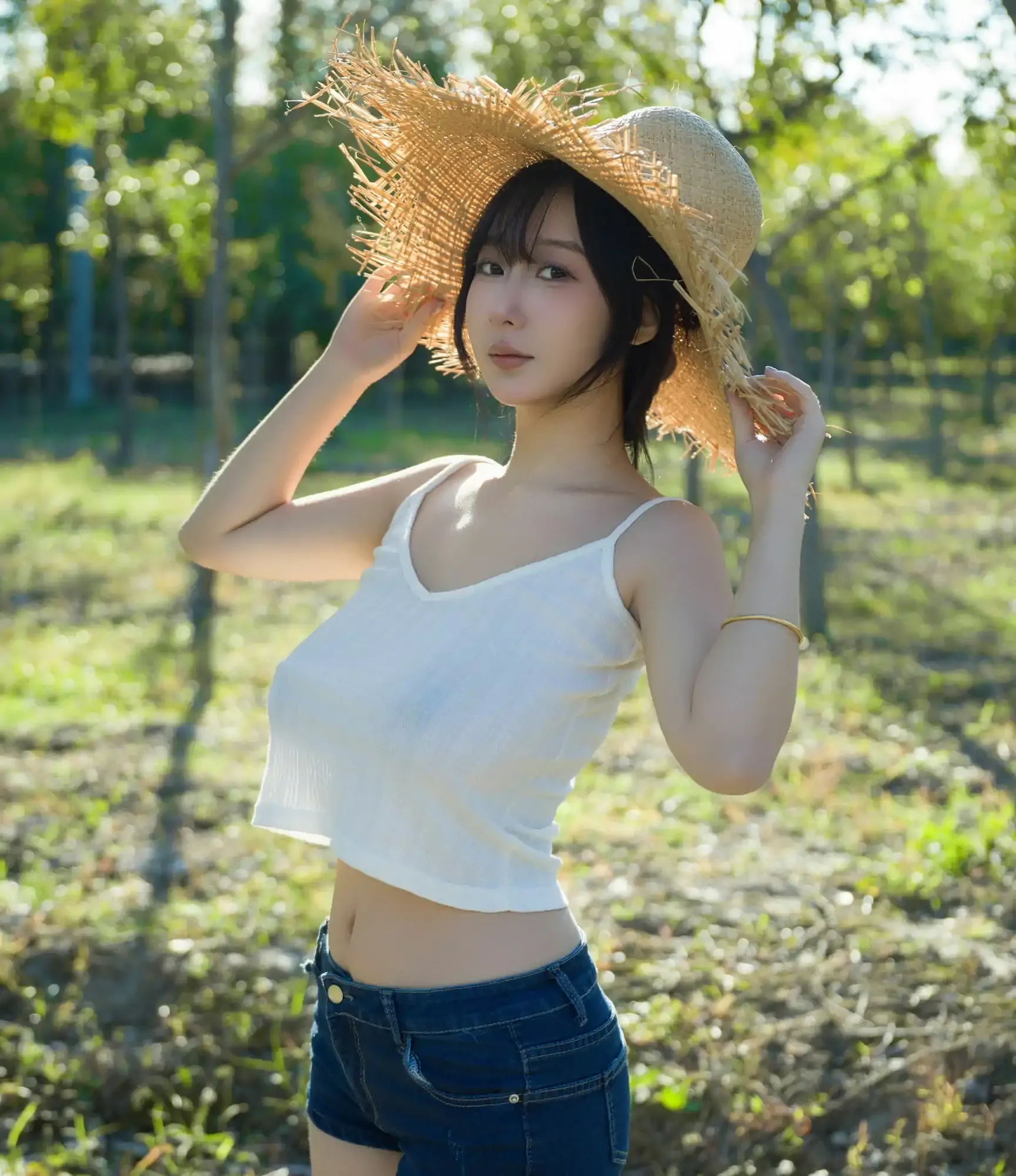 浅安安Yuki角色扮演与日常服装风格专题作品参考 户外树林中人物戴宽檐编织草帽，穿白色细肩带上衣和蓝色牛仔短裤，双手扶帽沿