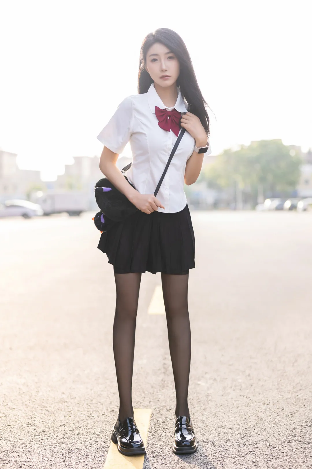 身穿白色衬衫黑裙制服立于公路分道线的苏苏阿