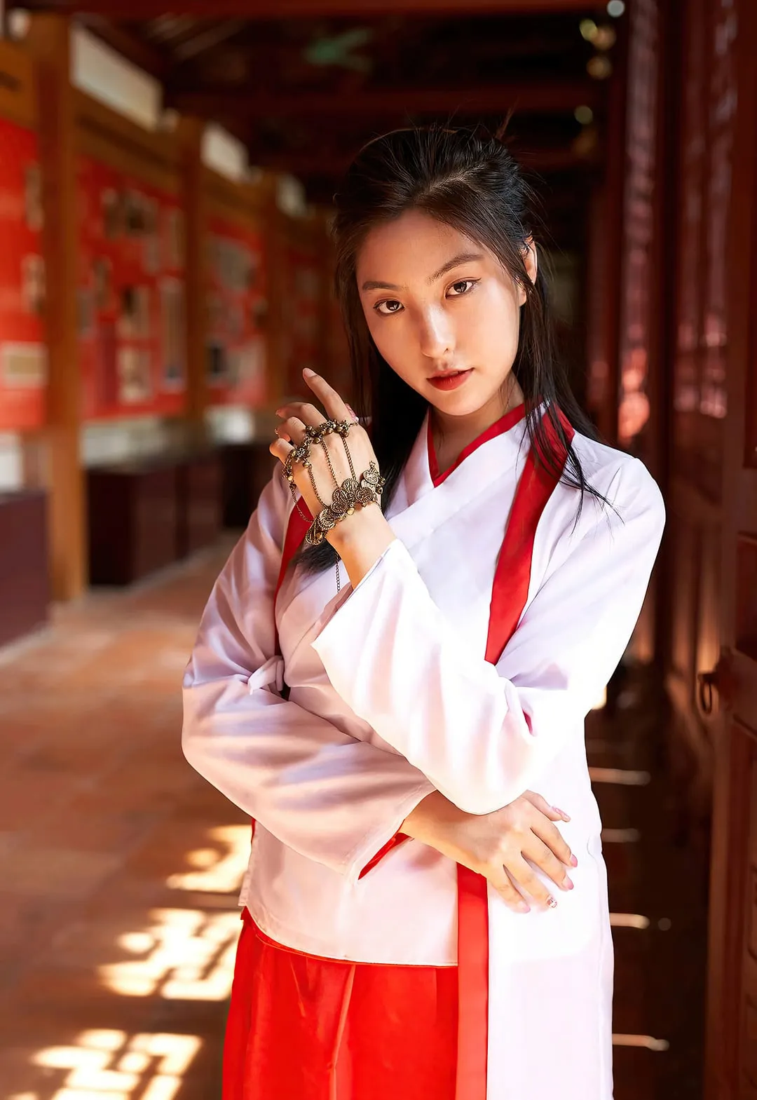 缇娜美身穿白红配色交领长衫在木质长廊中站立