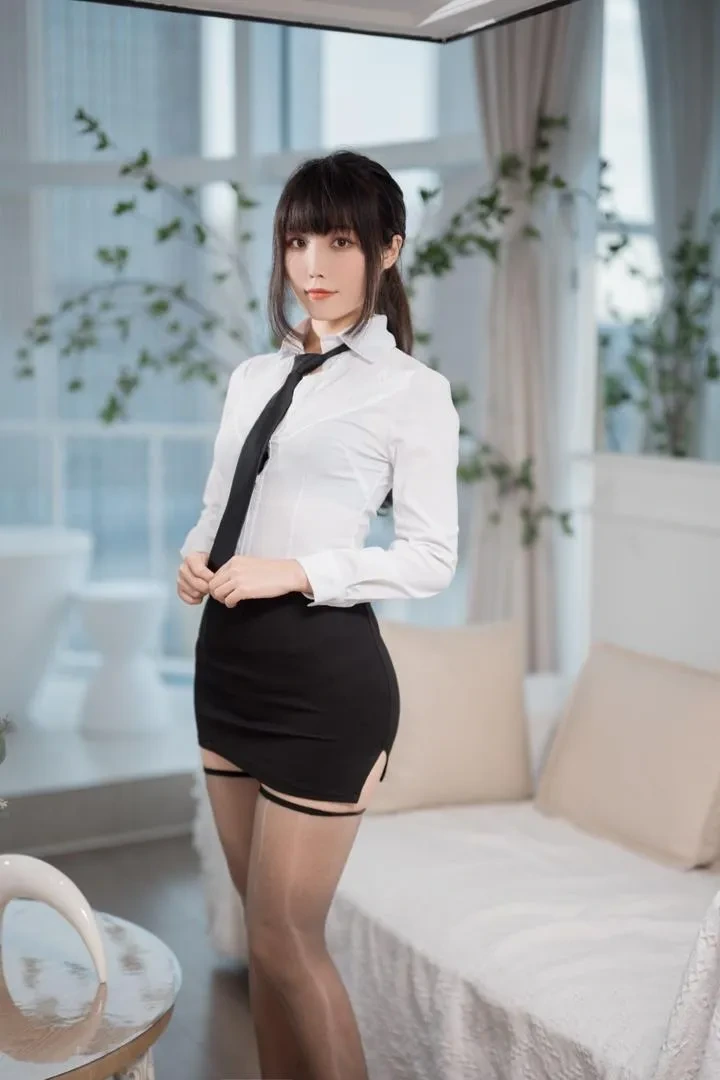 汪知子角色扮演制服与幻想造型风格专题 深色马尾刘海人物穿白衬衫、黑领带和黑色裙装,站在明亮室内,背景有浅色沙发、窗户和绿色植物